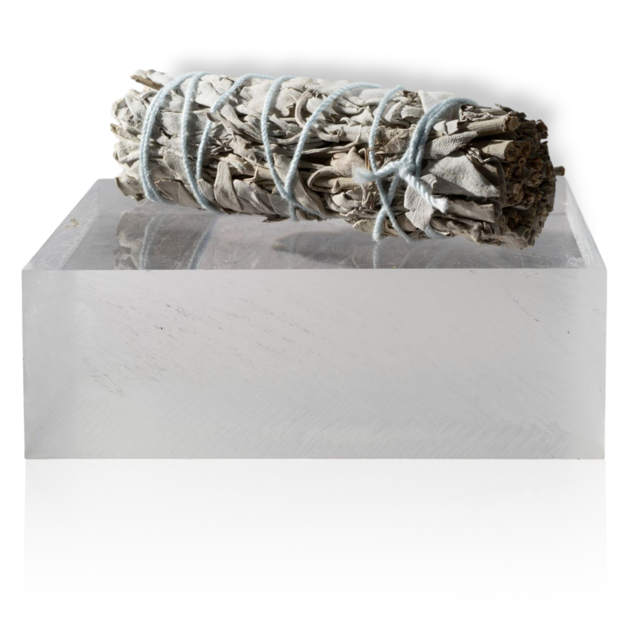 A sage smudge with a tightly bound bundle and a visible root, wrapped in brown paper, tied with string.