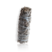 A sage smudge with a tightly bound bundle and a visible root, wrapped in brown paper, tied with string.